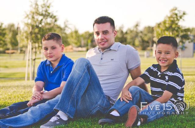 Mike sitting on the grass with his two young sons